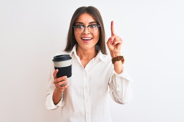 Wall Mural - Young businesswoman wearing glasses drinking coffee over isolated white background surprised with an idea or question pointing finger with happy face, number one