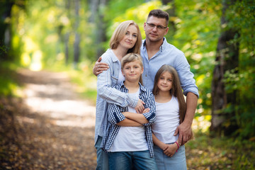 Portrait of happy family of four in a green summer park