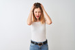 © Krakenimages.com - Beautiful redhead woman wearing casual t-shirt standing over isolated white background suffering from headache desperate and stressed because pain and migraine. Hands on head.
