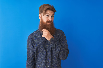 Poster - Young redhead irish man wearing floral summer shirt standing over isolated blue background looking confident at the camera smiling with crossed arms and hand raised on chin. Thinking positive.