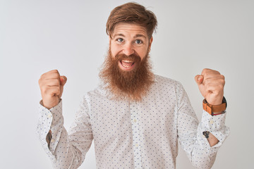 Poster - Young redhead irish man wearing shirt standing over isolated white background celebrating surprised and amazed for success with arms raised and open eyes. Winner concept.