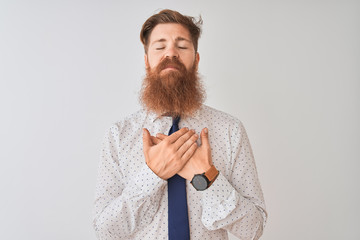 Poster - Young redhead irish businessman standing over isolated white background smiling with hands on chest with closed eyes and grateful gesture on face. Health concept.