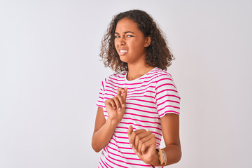 Canvas Print - Young brazilian woman wearing pink striped t-shirt standing over isolated white background disgusted expression, displeased and fearful doing disgust face because aversion reaction. With hands raised