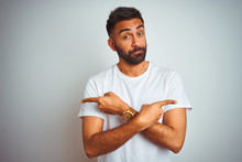 Young indian man wearing t-shirt standing over isolated white background Pointing to both sides with fingers, different direction disagree