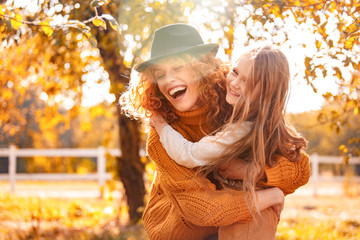 Young adult mother hugging her child girl outdoor