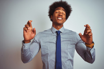 Sticker - American business man with afro hair wearing shirt and tie over isolated white background gesturing finger crossed smiling with hope and eyes closed. Luck and superstitious concept.