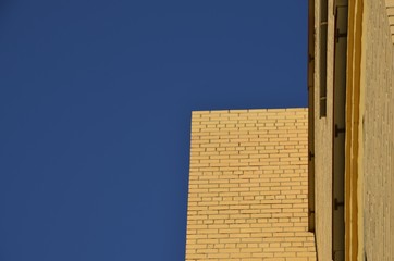 Against the blue sky built a modern new house. Brick wall view of the sky.