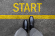 © yayha - Business man standing on street background with word new start written. Pair of feet and black shoes on tarmac road with yellow race line beginning idea concept. Top view. Businessman of starting.
