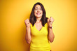 © Krakenimages.com - Young beautiful woman wearing t-shirt standing over yellow isolated background excited for success with arms raised and eyes closed celebrating victory smiling. Winner concept.