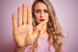Fototapeta  - Young beautiful woman wearing sweater standing over pink isolated background with open hand doing stop sign with serious and confident expression, defense gesture