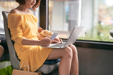 Wall Mural - Young businesswoman on a business travel. Working on the bus using her laptop.