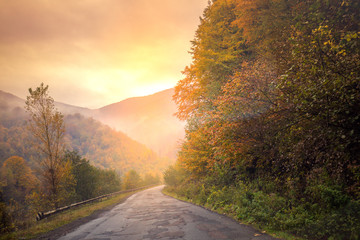 Autumn mountain scenery with beautiful light. Foggy morning. Mountain windy road among the forest