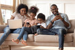 Black family with kids relax on couch using gadgets