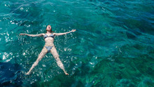 Young Slender European Girl In Swimsuit Swimming In Clear Blue Transparent Sea Water. She Enjoying Her Summer Holidays.
