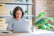 © Krakenimages.com - Middle age senior woman sitting at the table at home working using computer laptop with a happy face standing and smiling with a confident smile showing teeth