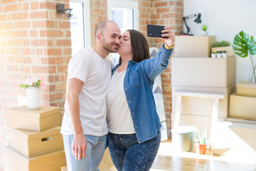 Young couple taking a picture photo using smartphone at new home, smiling happy for moving to new apartment