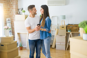 Young couple moving to a new house, using smartphone smiling very happy for new apartment