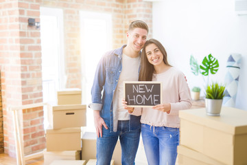 Poster - Beautiful young couple hugging in love and holding blackboard moving to a new home, smiling happy for new apartment