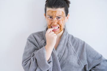 Sticker - Beautiful young woman wearing cosmetic facial mask as skincare beauty treatment looking stressed and nervous with hands on mouth biting nails. Anxiety problem.