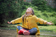 Happy child girl with  rubber boots in puddle