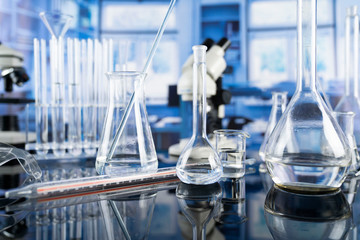 Modern scientific laboratory interior. Laboratory glassware and microscope on the glass table.