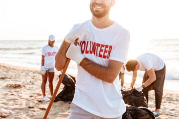 Wall Mural - Smiling young confident man volunteer cleaning beach