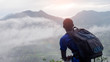 African man hiker with backpack at the top of the hill covered with mist.16:9 style
