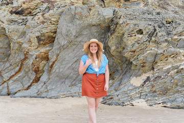 young woman in her 30s at currumbin beach wearing a big sun hat in Australia with large rock formations