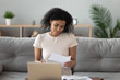 © fizkes - African American woman reading letter with good news at home