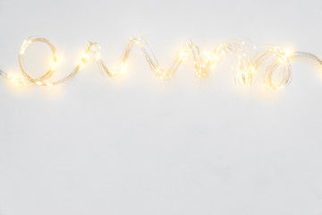 Christmas lights on white wooden background. Christmas and New Year holidays celebration concept