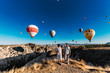 © MISHA - Couple in love stands on background of balloons in Cappadocia. The couple travels the world. Vacation in Turkey. Honeymoon trip. Hot air balloon flights. Happy young couple meets dawn in Cappadocia