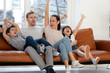 © fizkes - Overjoyed family of four watching football basketball match on tv.