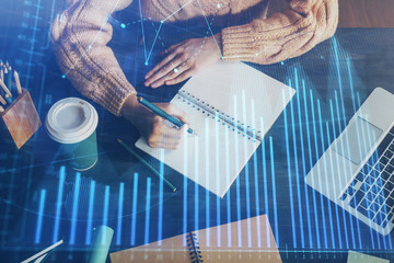 Forex graph on hand taking notes background. Concept of research. Double exposure