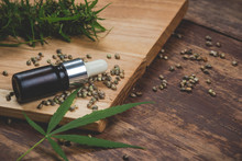 CDB Concept. Thai Cannabis. A Hemp Oil Bottle That Is Placed Combined With Seeds And Peaks On A Brown Wooden Floor.