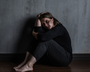 Wall Mural - Sad woman victim of domestic violence and abuse sits on a floor at home