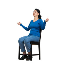 Casual Young Woman Sitting On A Chair, Eyes Closed, Hands Showing Zen Gesture Like Practicing Yoga Isolated Over White Background. Relaxed Girl Meditate And Calming Down.