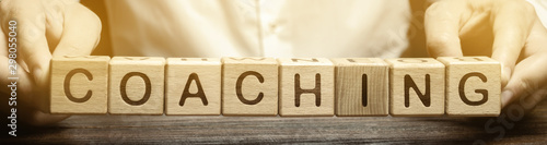 Fotomural Wooden blocks with the word Coaching in the hands of a man