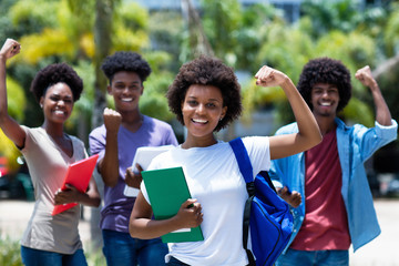 Wall Mural - Cheering african amerlcan female university student with group of african american students