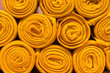 A pile of folded orange blankets. Rolls of orange blankets lie on a shelf, texture effect.