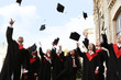 © New Africa - Happy students with diplomas throwing graduation hats in air outdoors
