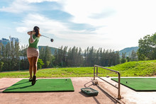 Healthy Sport.  Asian Sporty Woman Swing Golf Ball Practice At Golf Driving Range On Evening On Time For Healthy Sport. Lifestyle And Sport Concept.