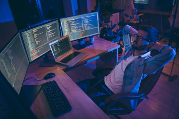 Portrait of his he nice attractive skilled expert guy monitoring remotely many projects online internet intranet blockchain start-up hardworking at dark room workplace station indoors