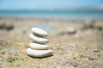 Pyramid of white stones on the empty beach against the sea