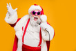 © deagreez - Portrait of fat big belly crazy funky santa claus hold microphones have live x-mas performance sing carols on christmas night wear red hat headwear trendy suspenders isolated yellow color background