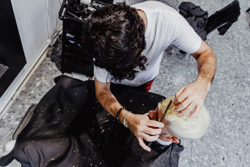 High angle shot of a hairdresser combing with a hair comb the dyed hair of a client in a barber shop