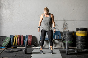 Strong young female weight lifter preparing for heavy lift in gym.