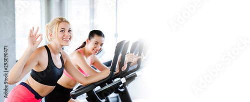 Fotomural Women wearing sportswear doing workout activity, spinning an electric bicycle in the gym For good health Have a beautiful shape And allowing the muscles to relax