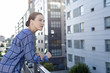 © Andres Victorero/ADDICTIVE STOCK - Side view of pretty female manager in checkered shirt smiling and looking away while standing on balcony of office building on sunny day in city