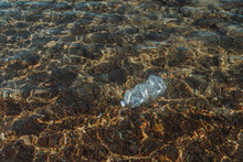 Empty Plastic Crumpled Bottles Waste Lying In Clear Water On Seaside Near Rocks