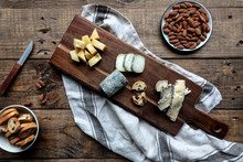 Sweet Croutons With Raisins And Plate With Almonds Placed On Wooden Table Near Board With Various Cut Cheese